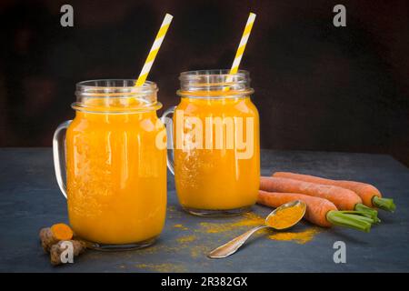 Smoothie à la carotte et au curcuma dans deux verres avec pailles Banque D'Images