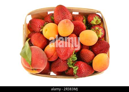 Fraises, abricots et pêche dans un panier en bois isolé sur blanc Banque D'Images