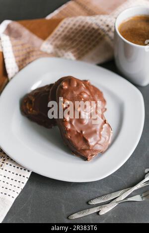 Biscuits aux noix enrobés de chocolat servis avec une tasse de café Banque D'Images