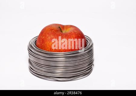 Apple filaire : ensemble pomme rouge dans des bobines de fil aluminium isolé sur fond blanc Banque D'Images