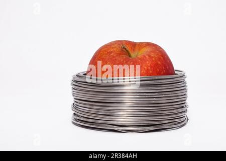 Apple filaire : ensemble pomme rouge dans des bobines de fil aluminium isolé sur fond blanc Banque D'Images