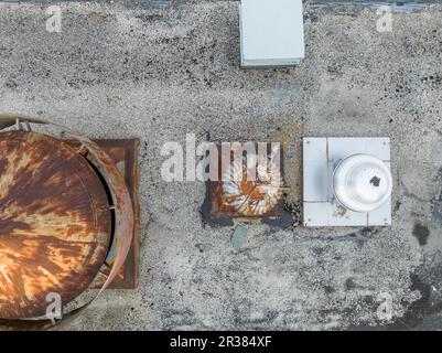 Vue aérienne d'un équipement HVAC rouillé d'aspect industriel sur un toit gris. Banque D'Images