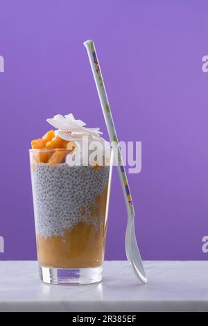 Gâteau au Chia avec purée de mangue et noix de coco dans un verre à dessert Banque D'Images