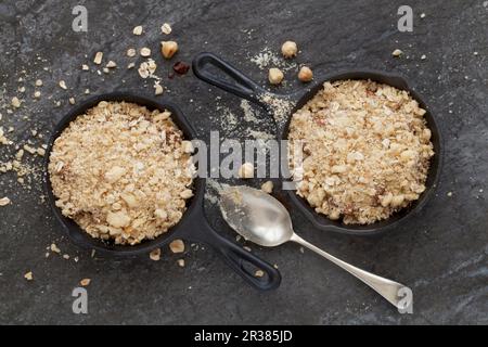 Crumble au chocolat et à la poire dans des haches en fonte (avant cuisson) Banque D'Images