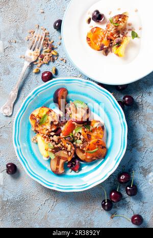 Pêches grillées, abricots, prunes, servies sur yaourt grec avec pistaches et orge Banque D'Images