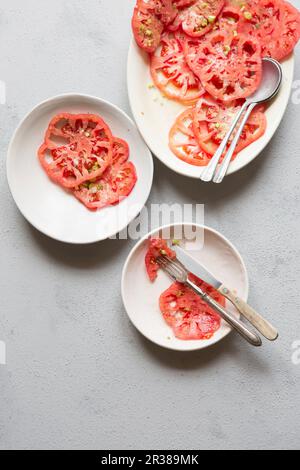 Salade de tomates roses avec oignons de printemps hachés, huile d'olive, origan séché et flocons de sel de mer Banque D'Images