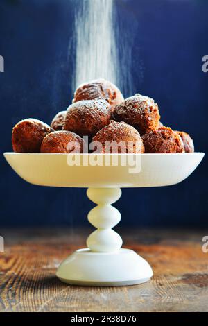 Le sucre glace étant saupoudré sur des beignets sur un étagère Banque D'Images