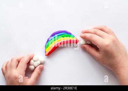 L'enfant sculpte un arc-en-ciel et des nuages à partir de la plasticine. La créativité des enfants. Banque D'Images