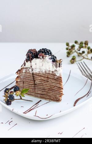 Une tranche de gâteau à la crêpe au chocolat et aux mûres Banque D'Images