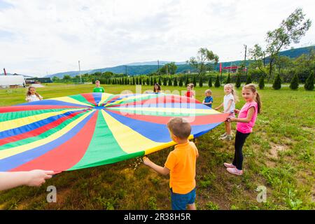 Enfants heureux répandre parachute coloré Banque D'Images