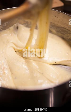 Un cuisinier prépare une sauce au fromage pour faire du fromage macaroni Banque D'Images