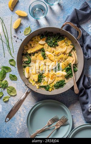 Un plat en pot, aiglefin fumé, pommes de terre en tranches, poireaux, œufs et ragoût d'épinards Banque D'Images