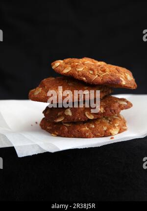 Une pile de biscuits d'avoine sur papier sur fond noir Banque D'Images