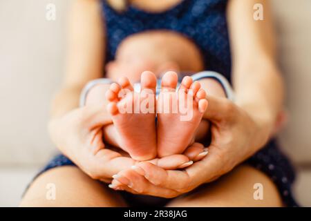 Mère détient les petits pieds de bébé nouveau-né Banque D'Images