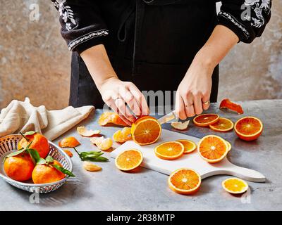 Une femme qui coupe des oranges sanguines Banque D'Images