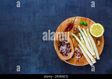 Asperges blanches et divers ingrédients pour une cuisine saine ou la préparation de salades sur bois rond sur fond d'ardoise vintage Banque D'Images