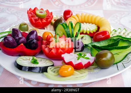 Assiette de plats végétariens pour le petit déjeuner avec concombre, tomate, olives vertes, spirale de pommes de terre, fromage jaune et poivron rouge sur le blanc Banque D'Images
