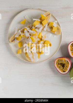 Bananes coupées en deux avec de la mangue, des fruits de la passion et de la noix de coco Banque D'Images