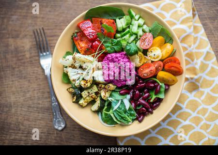 Bol de salade avec légumes rôtis au four, haricots et houmous de betteraves Banque D'Images