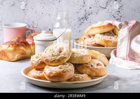 Fromage cottage traditionnel et petits pains aux groseilles Moravsky colac dans une assiette en céramique avec une bouteille de lait sur une table de cuisine grise Banque D'Images