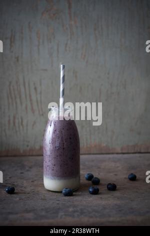 Smoothie aux noix de cajou et aux myrtilles végétaliennes dans une bouteille en verre Banque D'Images