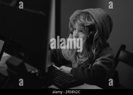 Petit garçon à l'écran de l'ordinateur de pc. Un enfant d'âge préscolaire  mignon regarde un film sur son bureau avant de dormir. Portrait d'un enfant  mignon tout en tapant sur le clavier