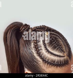 Cornouailles coiffure pour une fille avec des cheveux foncés, de minces tresses attachées dans une queue Banque D'Images