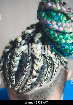 Une femme avec une coupe sur un fond blanc, les tresses serrées dans une queue tressée, matériau artificiel tissé dans ses cheveux Banque D'Images