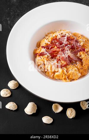 Assiette de pâtes d'orecchiette avec crème de potiron et bacon rôti Banque D'Images