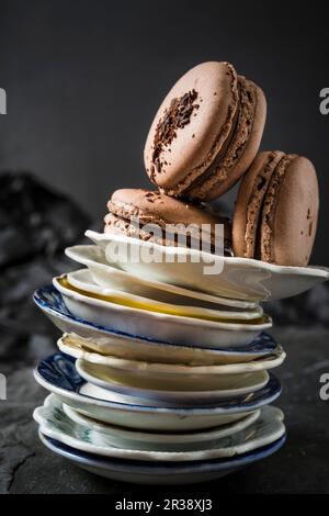 Trois macarons au chocolat sur une pile d'assiettes Banque D'Images