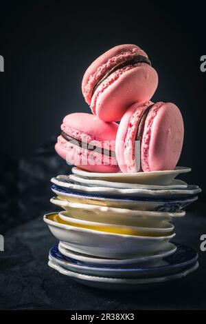 Trois macarons de framboise sur une pile d'assiettes Banque D'Images