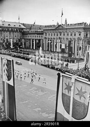 Jeux olympiques de Berlin 1936. Les Jeux Olympiques d'été 1936 (en allemand : Olympiche Sommerspiele 1936), officiellement connus sous le nom de Jeux de la XI e Olympiade (en allemand : Spiele der XI Olympiade), connue sous le nom de Berlin 1936, était un événement multisport international qui s'est tenu du 1 au 16 août 1936 à Berlin, en Allemagne. Photo de la flamme olympique transportée à l'Olympiastadion de Berlin par des coureurs sur la Pariser strasse à Berlin, sur le point de passer le Brandenburger Tor. Cette cérémonie est appelée relais de la torche olympique. Banque D'Images