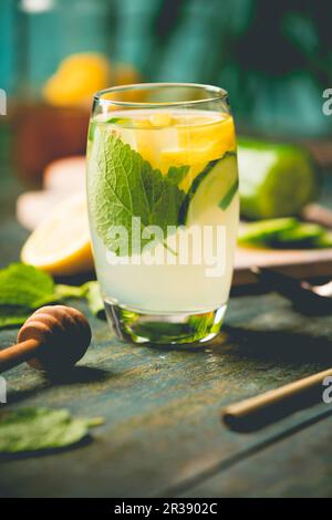 Eau fraîche et fraîche au concombre de citron, eau infusée au miel, cocktail, boisson détox, limonade dans un verre sur fond de bois Banque D'Images