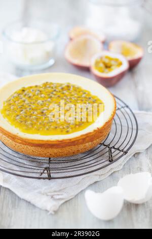 Cheesecake aux fruits de la passion sur une grille métallique, et divers ingrédients de cuisson Banque D'Images