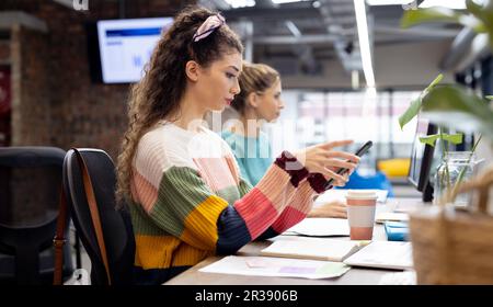 Occupé diverses femmes d'affaires travaillant au bureau utilisant un smartphone dans le bureau créatif, sans modification Banque D'Images