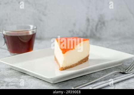 Cheesecake à la citrouille sur une assiette en porcelaine avec thé sur une table en pierre Banque D'Images