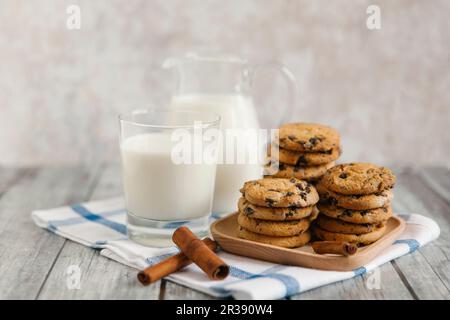 Du lait dans un pot et un pot, avec des biscuits aux pépites de chocolat et des bâtonnets de cannelle Banque D'Images