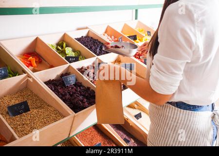 Jeune femme packs vendeur de fruits secs dans l'épicerie Banque D'Images