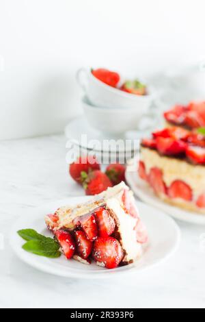 Gâteau à la fraise Fraisier sur l'assiette blanche et tasses pour le temps du thé, pièce coupée au premier plan Banque D'Images