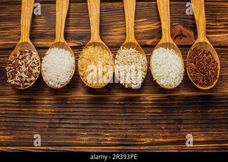 Vue de dessus des cuillères en bois avec différents types de riz Banque D'Images