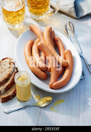 Saucisses avec des tankards à bière, un pot de moutarde et de pain Banque D'Images