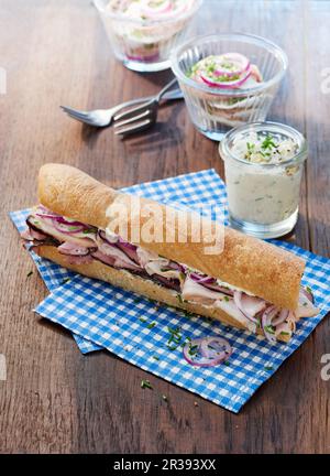 Un sandwich à la baguette avec du jambon, de la crème à la ciboulette et de la salade de viande dans un pot Banque D'Images