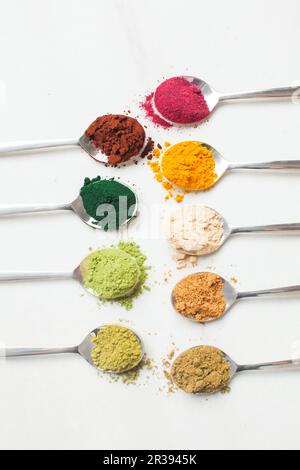 Ustensiles de cuisine avec différentes poudres de superalimentaire colorées sur table en bois Banque D'Images