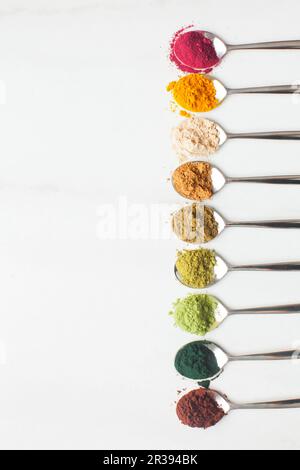 Divers types de poudres superalimentaires colorées sur table blanche Banque D'Images