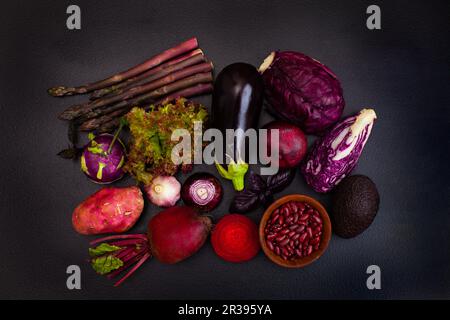 Tas de légumes violets crus sur le noir Banque D'Images