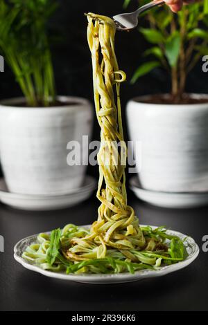 Pâtes avec arugula et pesto sur l'assiette, table noire Banque D'Images