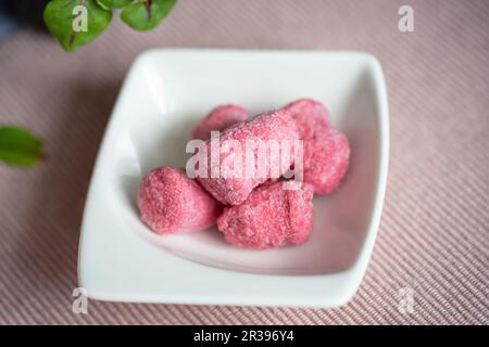 Gnocchi rose encore congelé (betterave) dans un petit bol blanc sur le tissu rose de la table. Banque D'Images