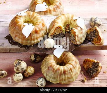 Mini-gâteaux de carottes et de poppyseed avec glaçage pour Pâques avec des petits pains de Pâques et des œufs de caille Banque D'Images