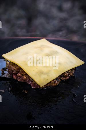 Une patty hamburger garnie de fromage dans une poêle à grillades Banque D'Images