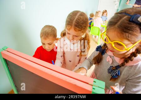 Les enfants jouent avec des chiffres magnétiques en plastique sur le tableau Banque D'Images